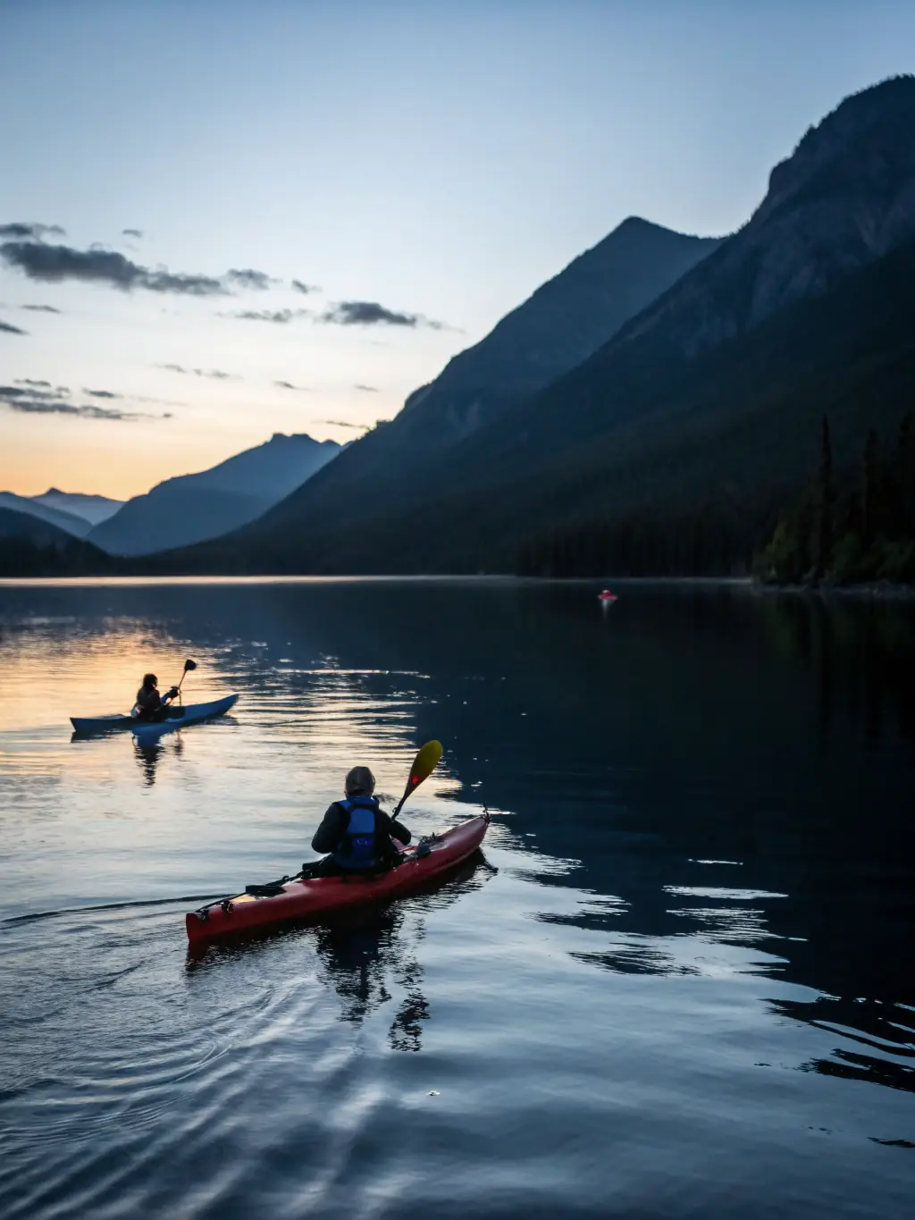 A scenic view of participants kayaking on a calm lake surrounded by mountains, illustrating the adventure and exploration offered by UCPA SPORT VACANCES.